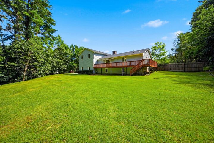 Backyard lawn with trees and the house’s raised deck at 7 Twin Street, Windham, NH
